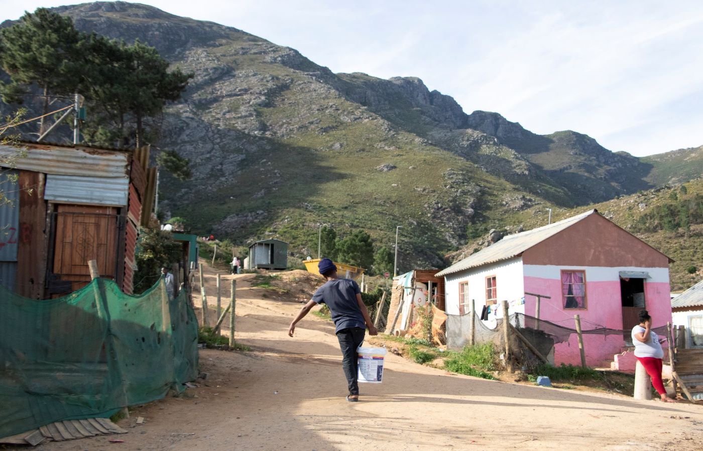 adult carrying water bucket up hill
