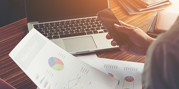 Business man with phone, laptop and graphs image designed JComp / Freepik
