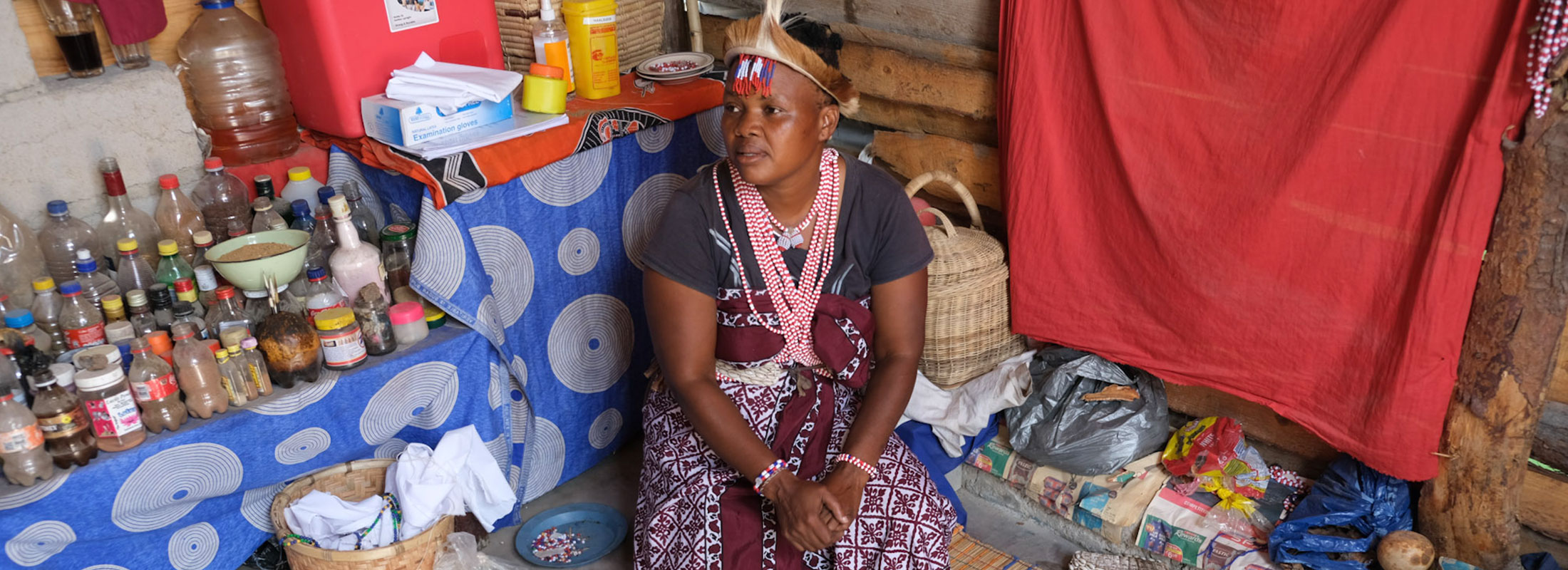 Traditional healer Gogo Lucia sits in front of her muti table and her HIV-testing kit