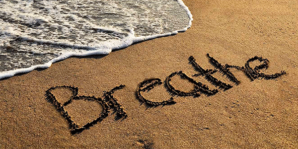 Beach with breathe written in the sand