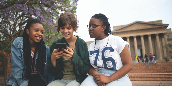 Students looking at phone outside Great Hall_image credit Shivan Parusnath